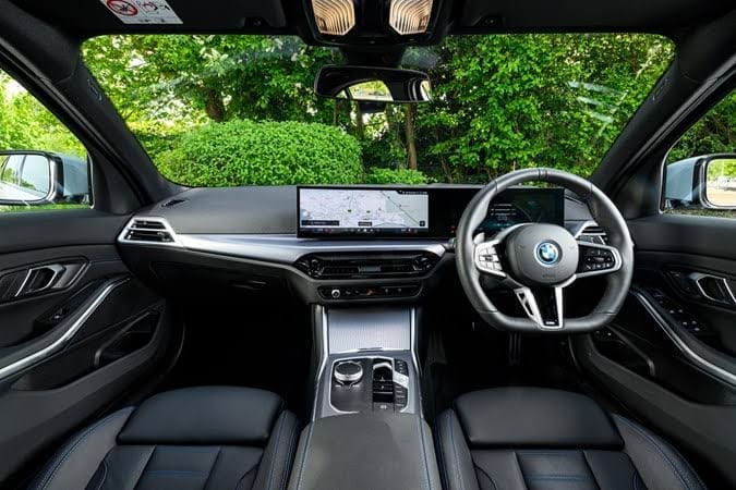 Bmw 330e M Sport 20264 | ยางรถยนต์ ราคาอัปเดต 2026 ครบทุกยี่ห้อ รวมยาง Ev | Autotirechecking Luxurious BMW interior with a curved dashboard, dual screens, and a leather-clad cockpit from the back seat.