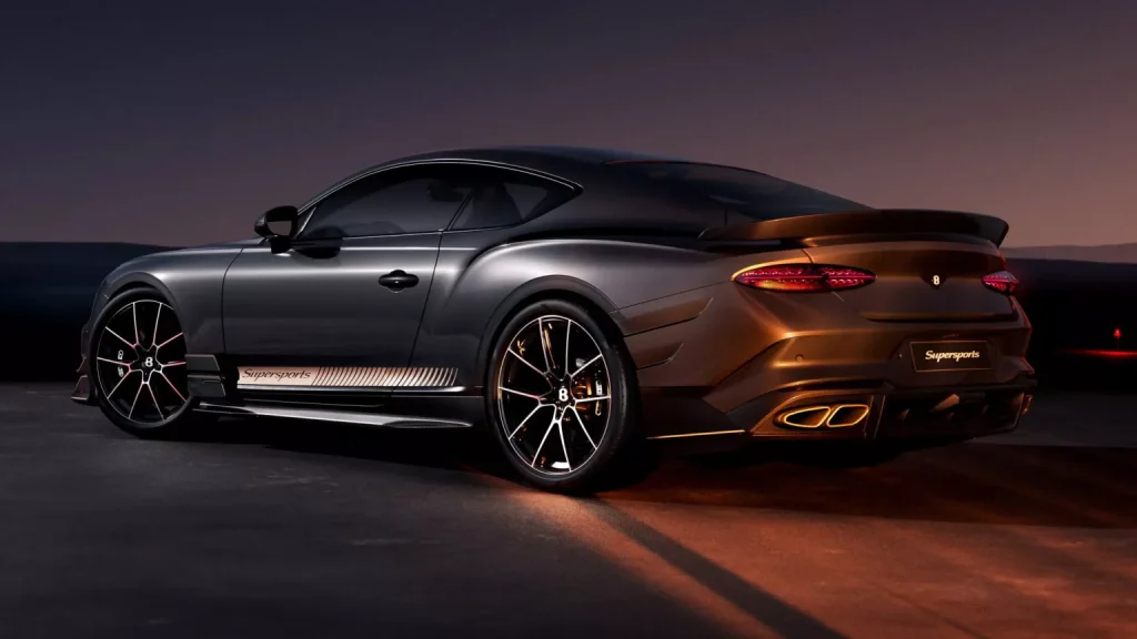 Rear three-quarter view of a dark gray Bugatti Chiron Super Sport coupe with orange underglow and a rear spoiler on a nighttime tarmac.