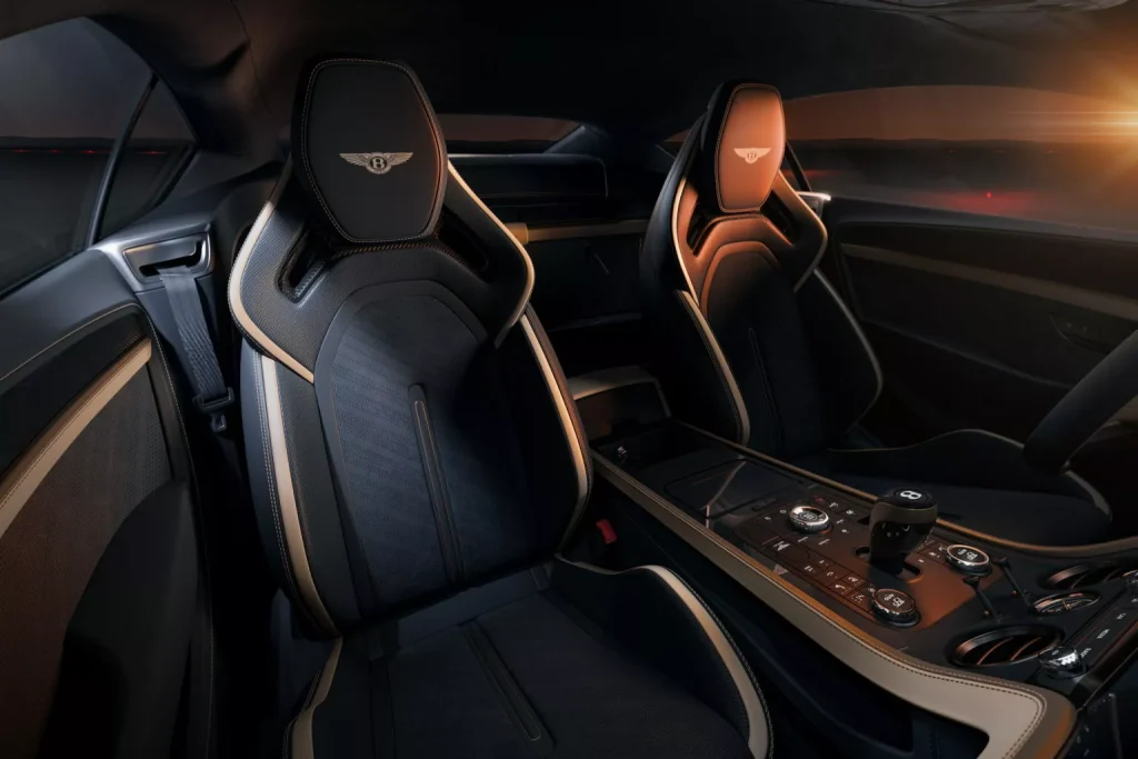 Front cabin of a Bentley with black and tan leather sport seats and a central control console.