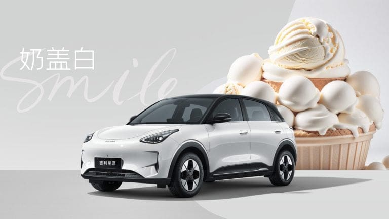 White electric SUV in front of a giant ice cream dessert backdrop with the word 'smile' in cursive text.