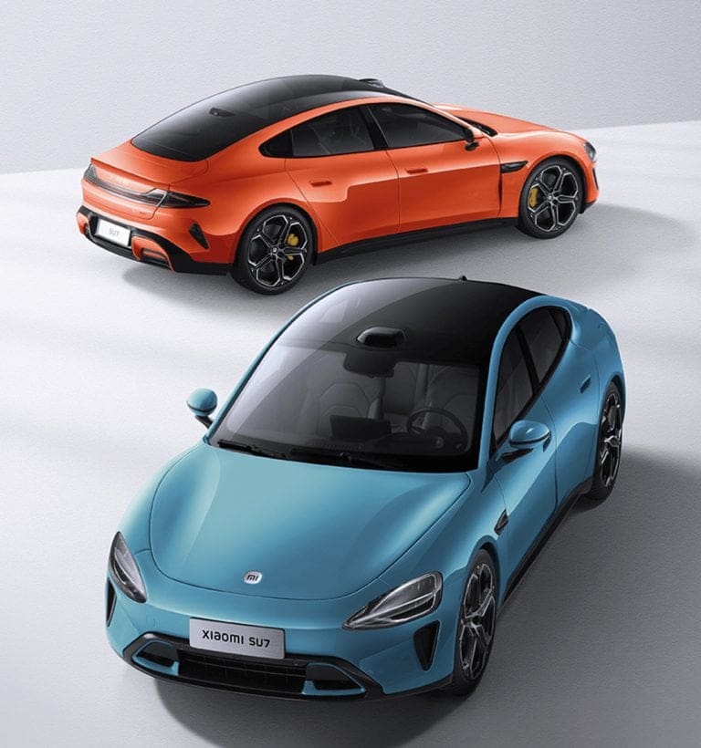 Two sports cars seen from above: a blue sedan in front and an orange SUV behind, on a light surface.