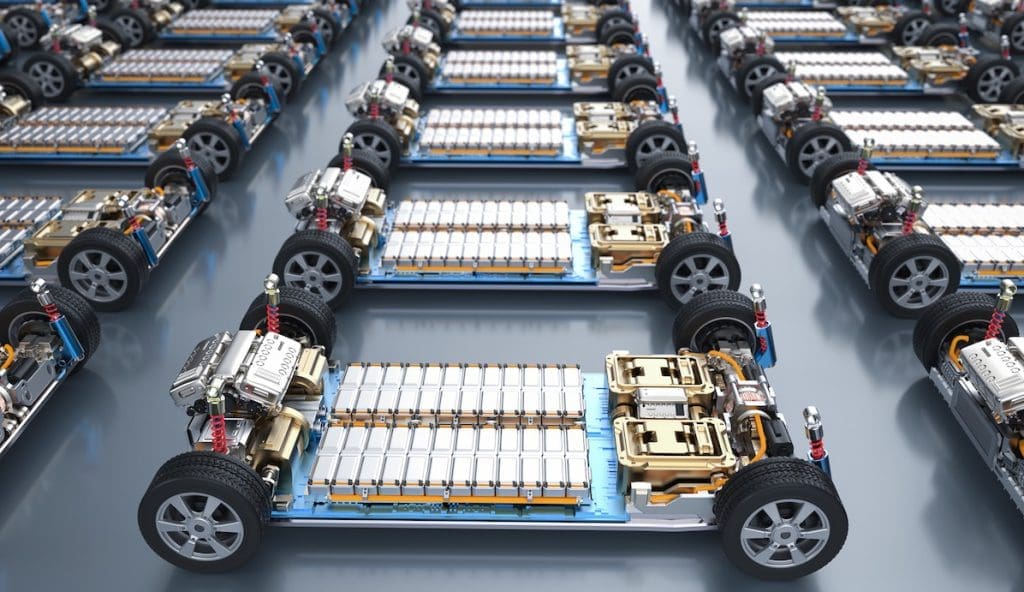 Group of Electric Cars with Pack of Battery Cells Module on Platform | ยางรถยนต์ ราคาอัปเดต 2026 ครบทุกยี่ห้อ รวมยาง Ev | Autotirechecking Rows of electric vehicle battery packs mounted on chassis in a manufacturing facility, aligned in neat rows for assembly/testing.