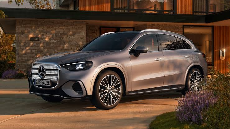Img4592 | ยางรถยนต์ ราคาอัปเดต 2026 ครบทุกยี่ห้อ รวมยาง Ev | Autotirechecking Silver Mercedes-Benz SUV parked in a driveway in front of a modern stone-and-glass house during golden hour tax lighting.