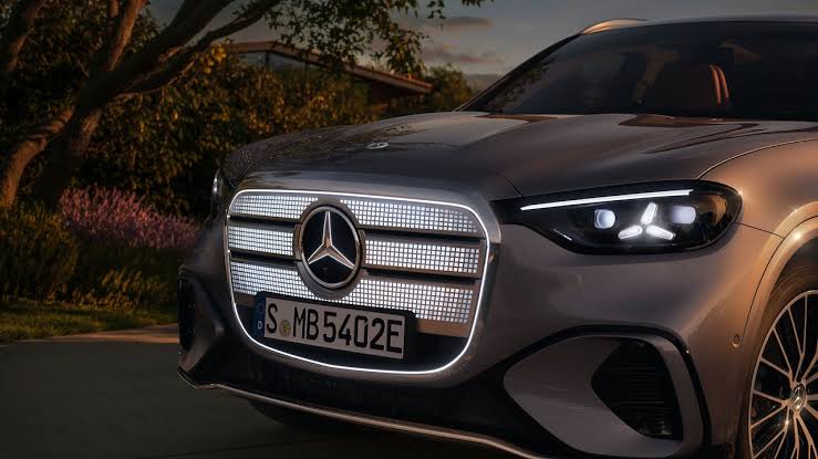 Front view of a silver Mercedes with a prominent illuminated grille and LED headlights; license plate reads S MB5402E