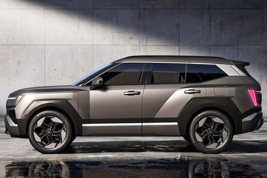 Img4866 | ยางรถยนต์ ราคาอัปเดต 2026 ครบทุกยี่ห้อ รวมยาง Ev | Autotirechecking Side profile of a modern gray SUV with bold angular lines parked on a wet, reflective surface near a concrete wall.