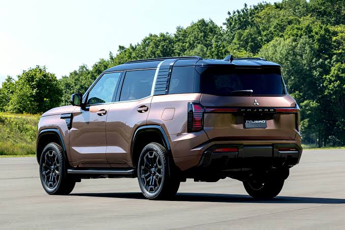 Rear three-quarter view of a bronze SUV parked on a paved surface with trees in the background (Pajero badge visible).