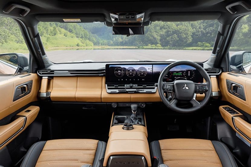 Front interior of a Mitsubishi SUV with tan leather seats, a wide digital instrument cluster, and center touchscreen