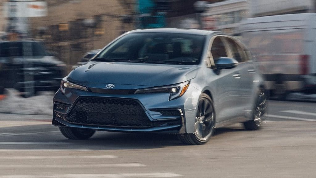 Img4882 | ยางรถยนต์ ราคาอัปเดต 2026 ครบทุกยี่ห้อ รวมยาง Ev | Autotirechecking Front three-quarter view of a silver Toyota sedan driving through a city street.