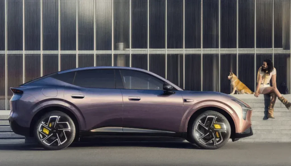 Img4926 | ยางรถยนต์ ราคาอัปเดต 2026 ครบทุกยี่ห้อ รวมยาง Ev | Autotirechecking Metallic purple luxury crossover car parked beside a glass-fronted building; a woman sits on steps with a corgi nearby.