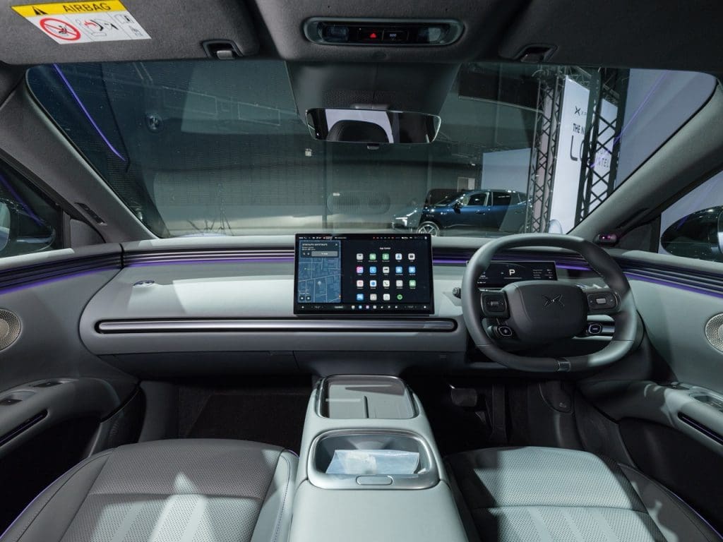 Img4928 | ยางรถยนต์ ราคาอัปเดต 2026 ครบทุกยี่ห้อ รวมยาง Ev | Autotirechecking Luxurious car interior with a large tablet-style infotainment screen on the dash and purple ambient lighting across the dashboard, steering wheel on the right side.