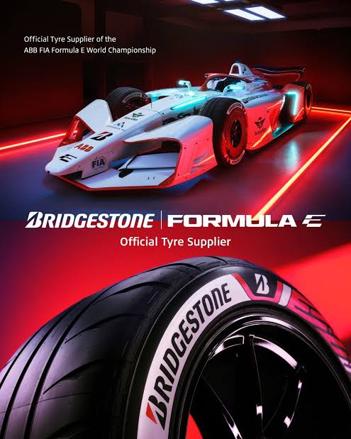 Img5029 | ยางรถยนต์ ราคาอัปเดต 2026 ครบทุกยี่ห้อ รวมยาง Ev | Autotirechecking White Formula E race car on a red-lit stage with a large Bridgestone tire in the foreground; shows'Official Tyre Supplier' branding.
