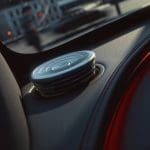 Img5149 | ยางรถยนต์ ราคาอัปเดต 2026 ครบทุกยี่ห้อ รวมยาง Ev | Autotirechecking Close-up of a round car speaker on the door panel, with red ambient lighting along the dashboard edge behind it.