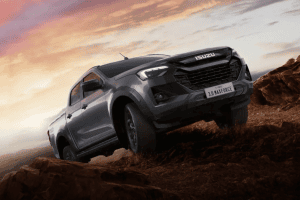 Isuzu pickup climbing a rocky hillside at sunset, off-road adventure scene