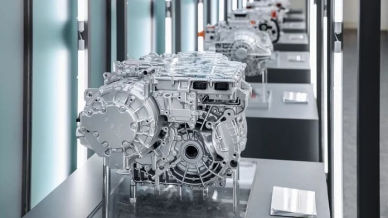 Row of gray automotive transmission units on display in a museum-like showroom.