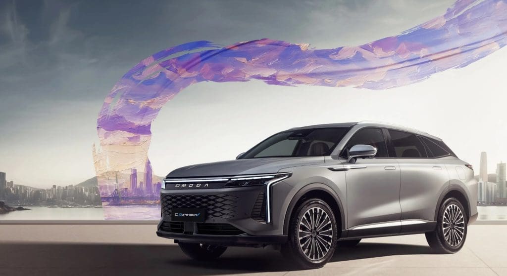 Omoda C9 Phev 20261 | ยางรถยนต์ ราคาอัปเดต 2026 ครบทุกยี่ห้อ รวมยาง Ev | Autotirechecking Silver SUV parked on a waterfront street with a large purple abstract sculpture arch in the background