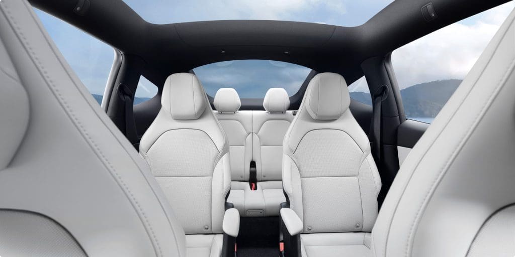 Interior of a modern white leather SUV with two front seats and a back row, panoramic sunroof, and light gray upholstery.