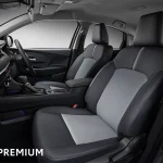 Front cabin of a modern car with black/gray upholstered seats, center console, and a touchscreen on the dashboard.