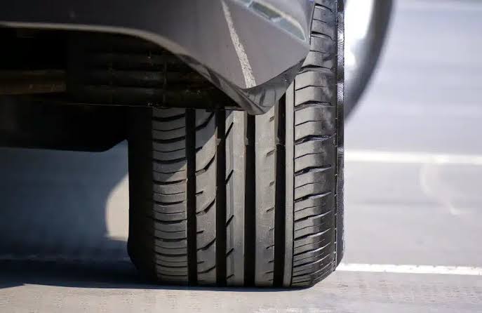 ยางรถไฟฟ้า1 | ยางรถยนต์ ราคาอัปเดต 2026 ครบทุกยี่ห้อ รวมยาง Ev | Autotirechecking Close-up of a car tire with visible tread resting on a parking lot surface with white parking lines